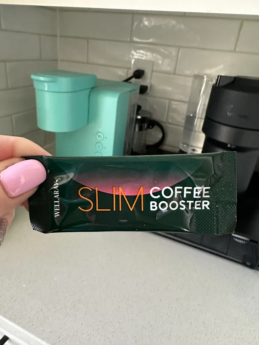 Slim Coffee Booster Stick vor einer Kaffeemaschine in der Küche